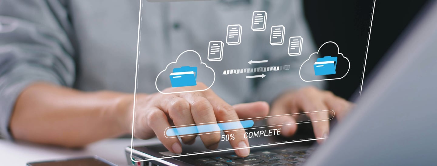 A man typing on a laptop. A graphic representing data migration hovers over the keyboard.