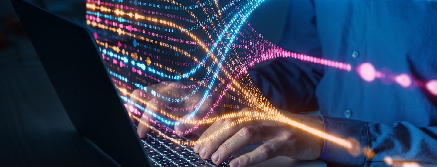 Hands typing a a laptop. streams of data (1s and 0s) in multiple colors form and coalesce in abstract lines above the keyboard.