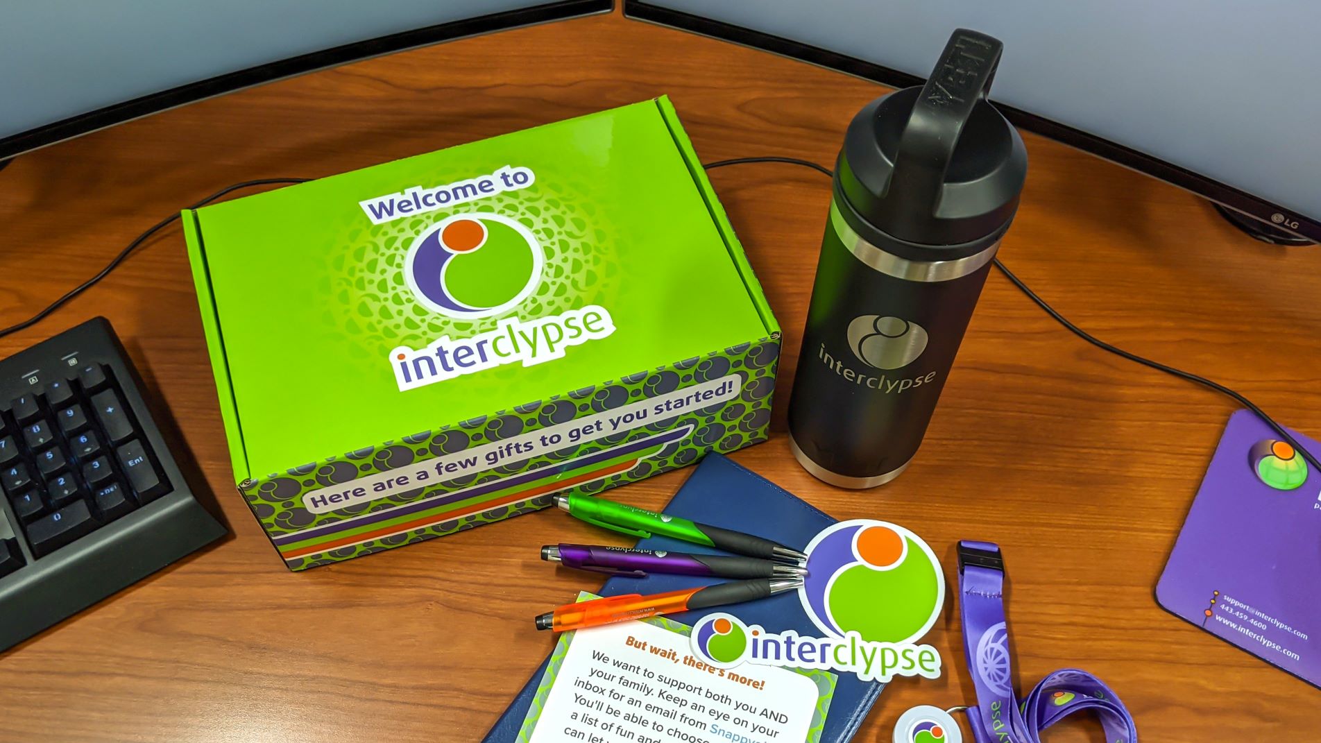 Interclypse Welcome kit featuring pens, stickers, engraved yeti thermos, lanyard, notebook, and a card directing new employees to check their emails for a Snappy gifts email.